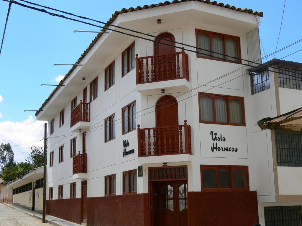un edificio blanco con balcones rojos en una calle en Hostal Vista Hermosa, en Chachapoyas