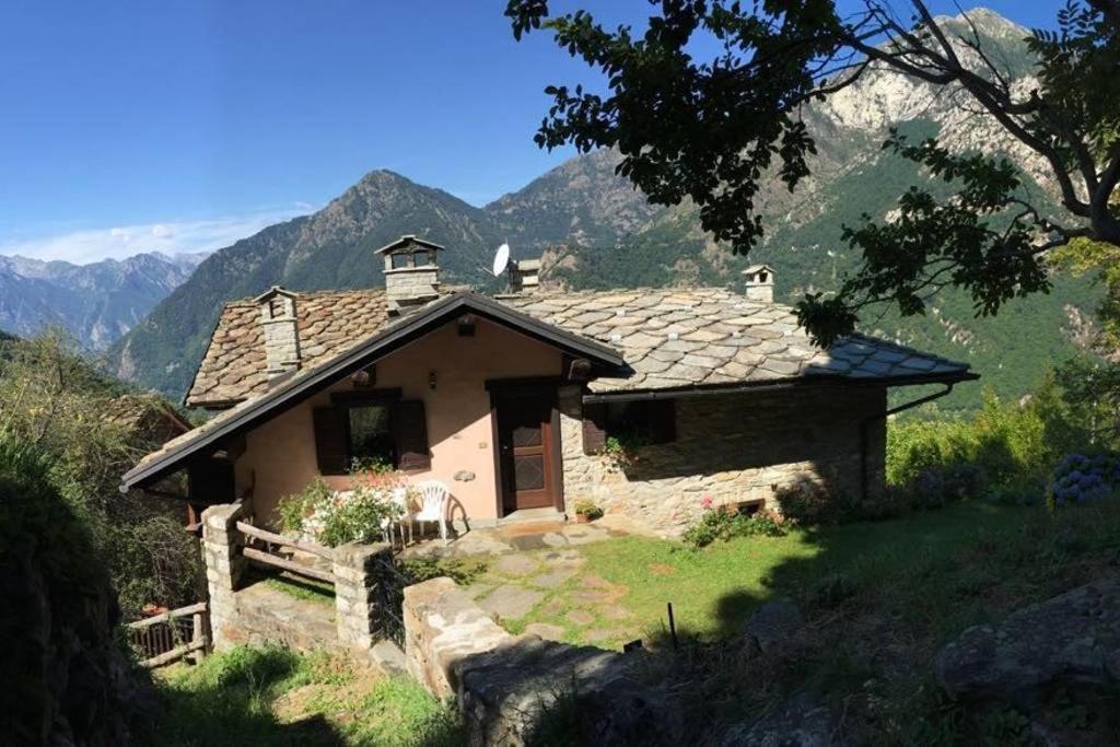 una piccola casa su una collina con montagne sullo sfondo di Rascard - Valle di Gressoney a Lillianes