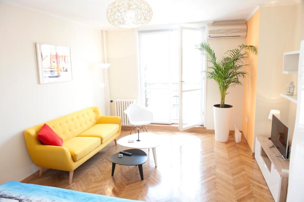 un soggiorno con un divano giallo e una TV di Atelje apartment a Belgrado