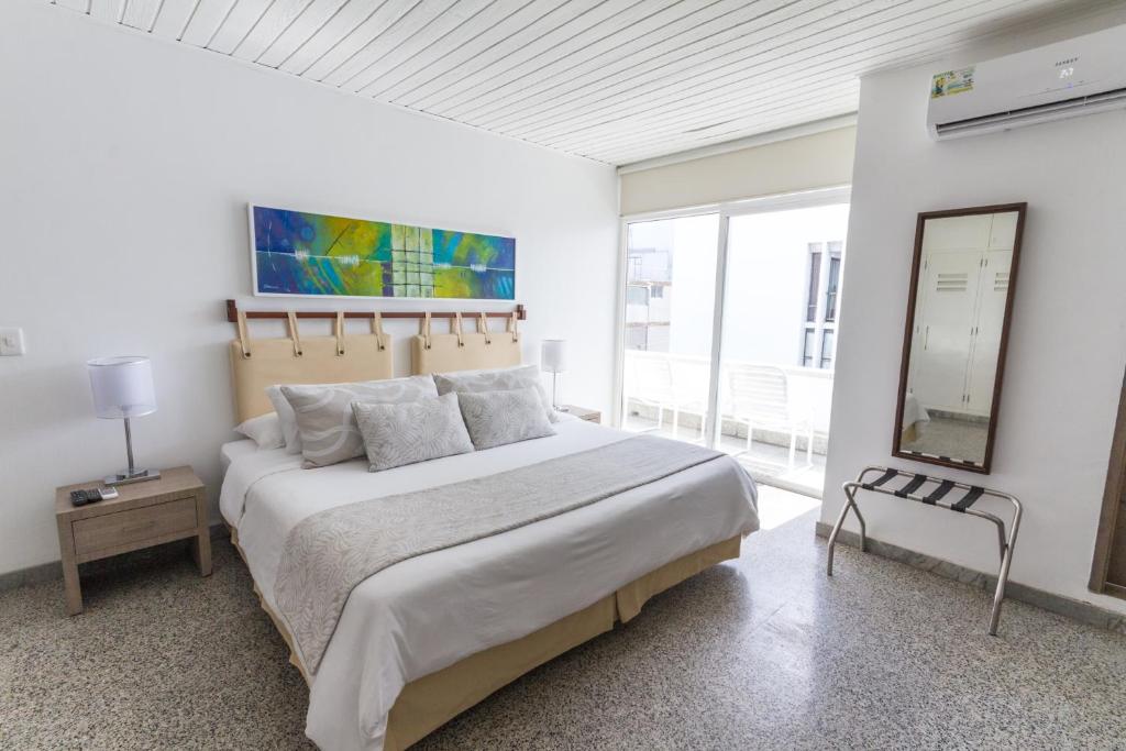1 dormitorio blanco con 1 cama grande y espejo en Apartamento Vip Edificio Calima, en San Andrés