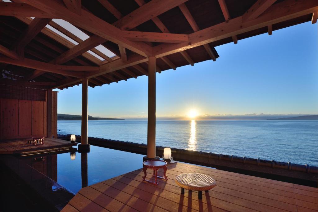 eine Terrasse mit Meerblick, einem Tisch und Stühlen in der Unterkunft Bousui in Higashiizu