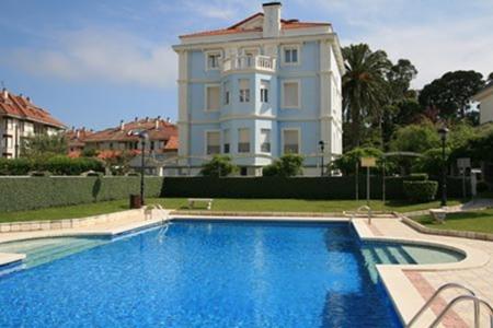 a large house with a swimming pool in front of a house at Apartamentos Villa de Noja in Noja