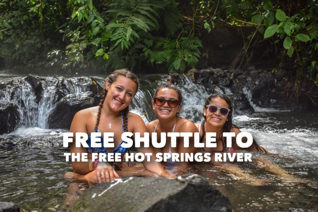 three people in a waterfall with the text free shuttle to the free hot springs river at Hotel La Choza Inn in Fortuna