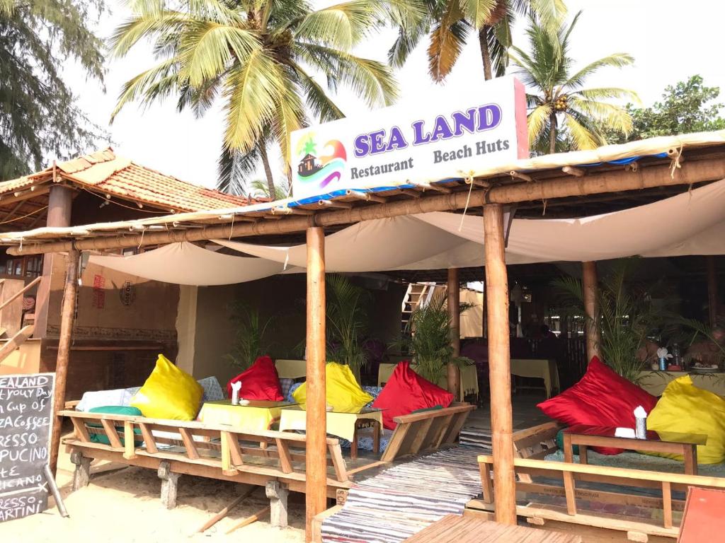 un restaurant avec des chaises colorées sur une terrasse en bois dans l'établissement Sealand Beach Cottages, à Patnem