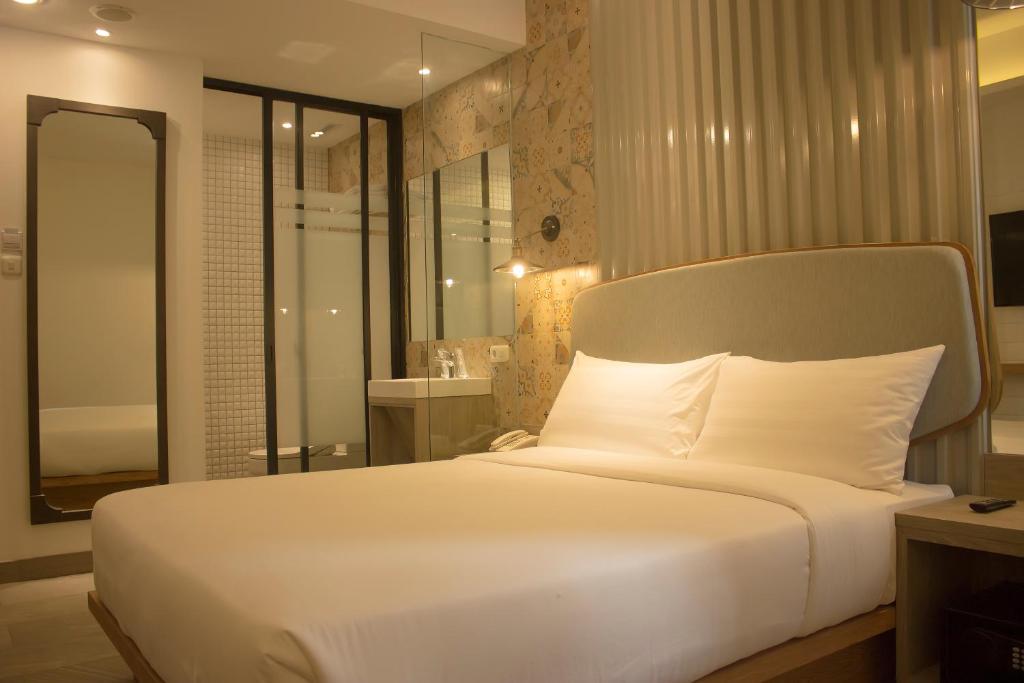 a bedroom with a large white bed and a bathroom at Ana Hotel Jakarta in Jakarta