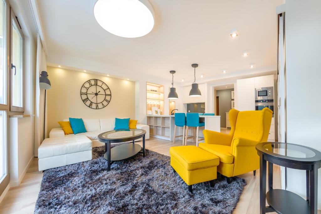 a living room with yellow chairs and a white couch at Apartamenty Sun & Snow Zdrojowa in Świnoujście