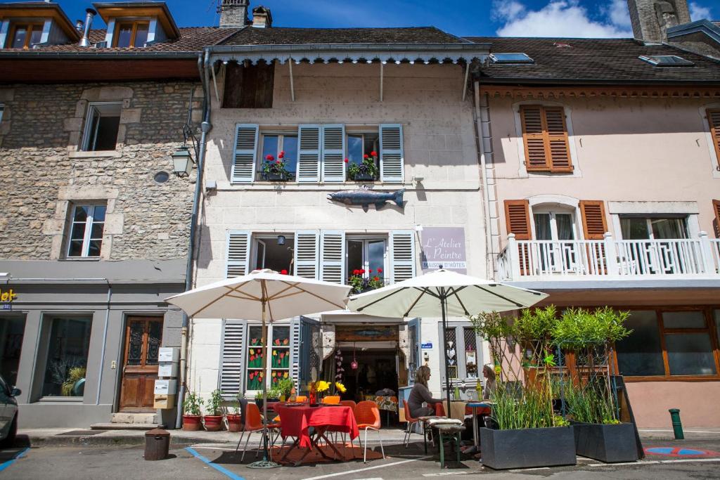 dos mesas con sombrillas frente a un edificio en L'Atelier Du Peintre, en Ornans