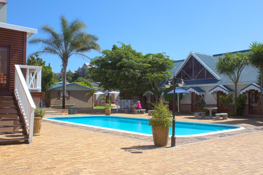 a swimming pool in front of a house at Oceans Hotel & Self Catering in Mossel Bay