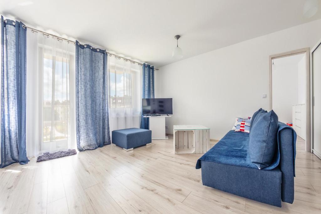 a living room with a blue couch and a tv at Apartamenty Sun & Snow Kwartał Róży Wiatrów in Świnoujście
