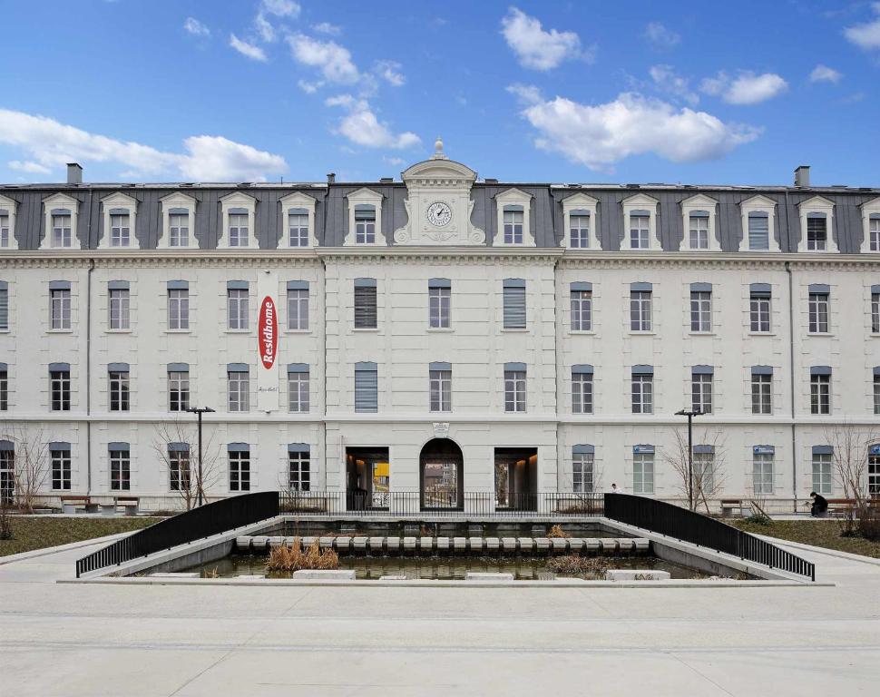Un grand bâtiment blanc avec des escaliers se trouve juste devant. dans l'établissement Residhome Grenoble Caserne De Bonne, à Grenoble