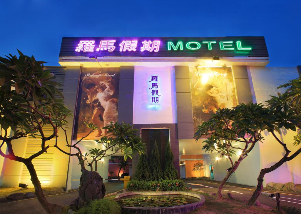 a hotel with a neon sign in front of it at Roman Vacation Motel in Dali