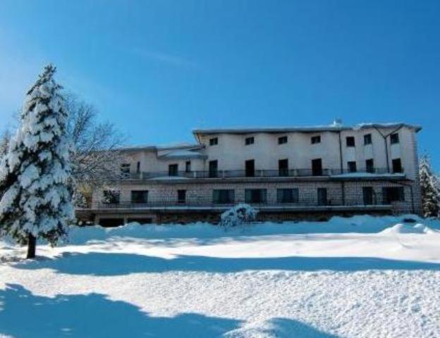 un bâtiment recouvert de neige avec un arbre devant lui dans l'établissement Hotel El Senor, à Pretoro