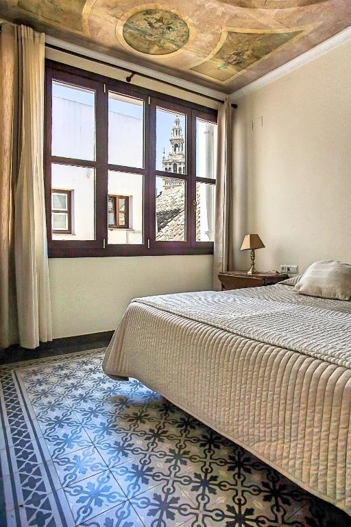 sypialnia z dużym łóżkiem i oknem w obiekcie Angeles House w Sewilli