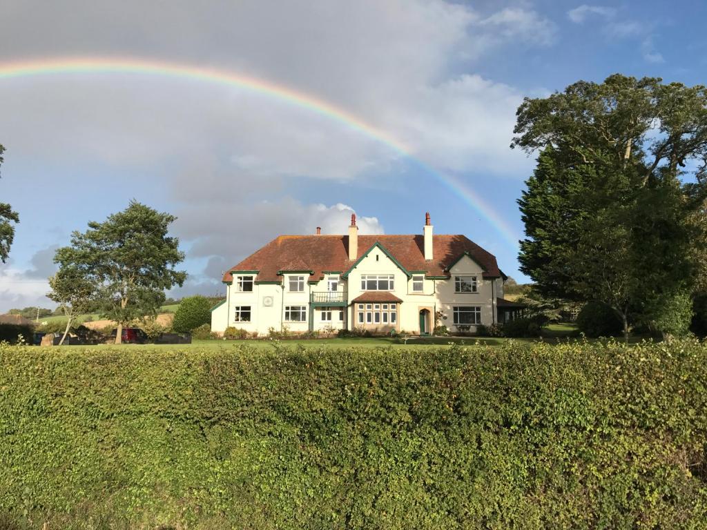 um arco-íris sobre uma casa branca com um campo em Cedar House em Minehead