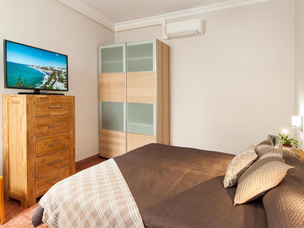 um quarto com uma cama e uma cómoda com uma televisão em Beautiful Beach Apartment M&B IV by Las Canteras em Las Palmas de Gran Canárias