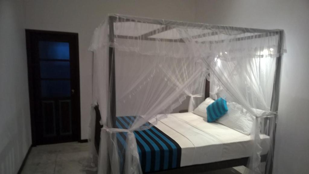 a bedroom with a canopy bed with blue and white pillows at Silva Rest in Unawatuna