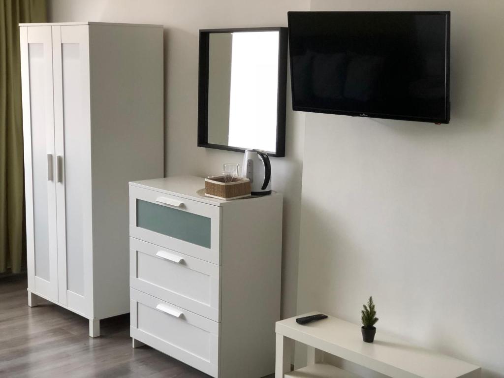 a white dresser with a mirror and a tv on a wall at Terra Guest House in Velingrad