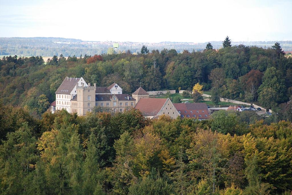 un gran edificio en la cima de una colina con árboles en Schloss Weitenburg, en Starzach