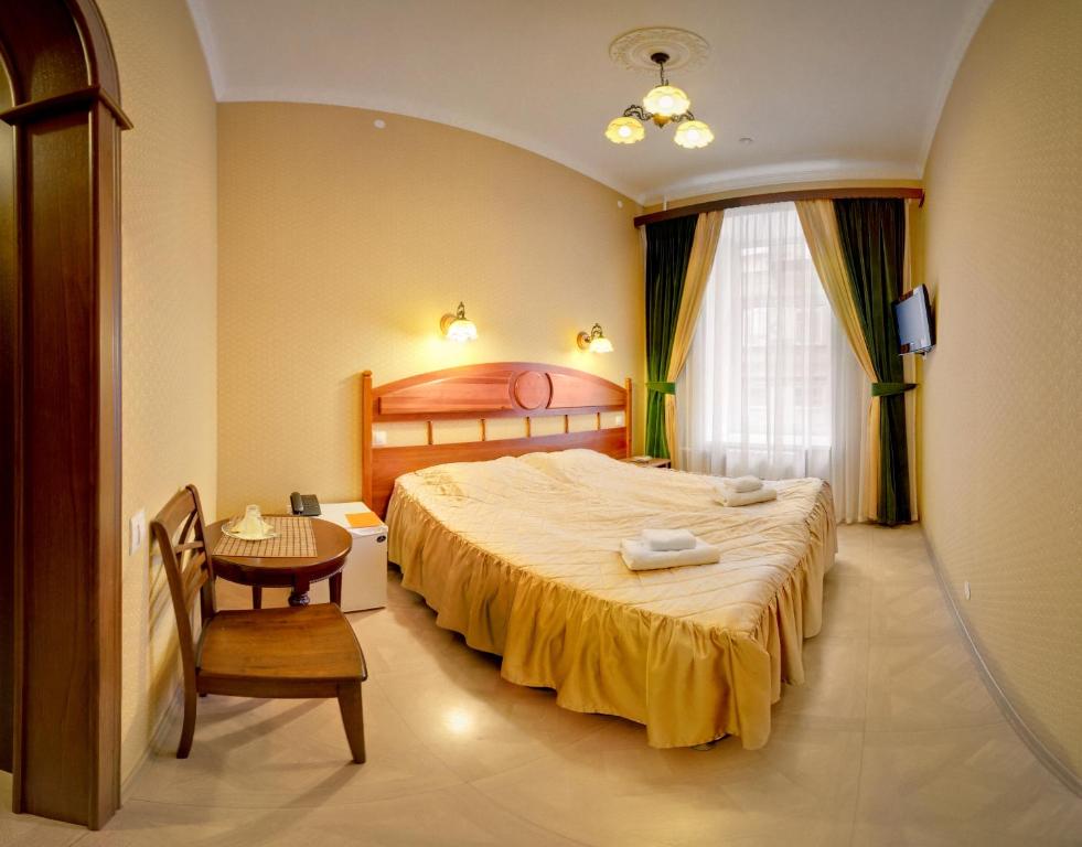 ein Schlafzimmer mit einem Bett, einem Tisch und einem Stuhl in der Unterkunft Hotel Adeliya in Sankt Petersburg