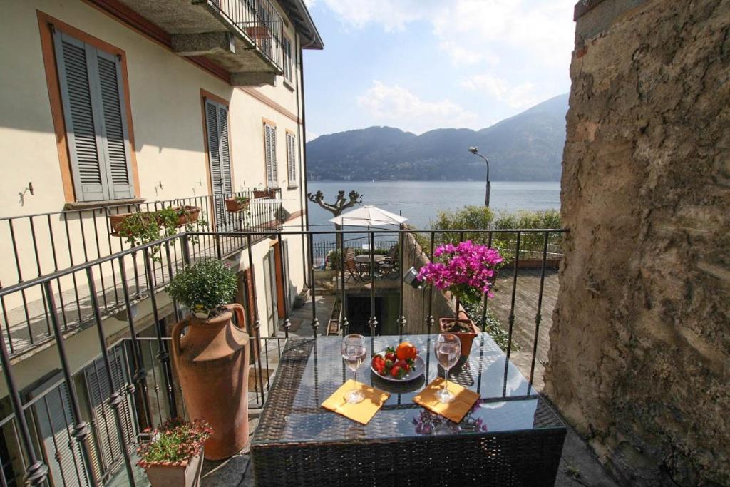 a balcony with a table with wine glasses and flowers at Little Luxury Suite in Tremezzo