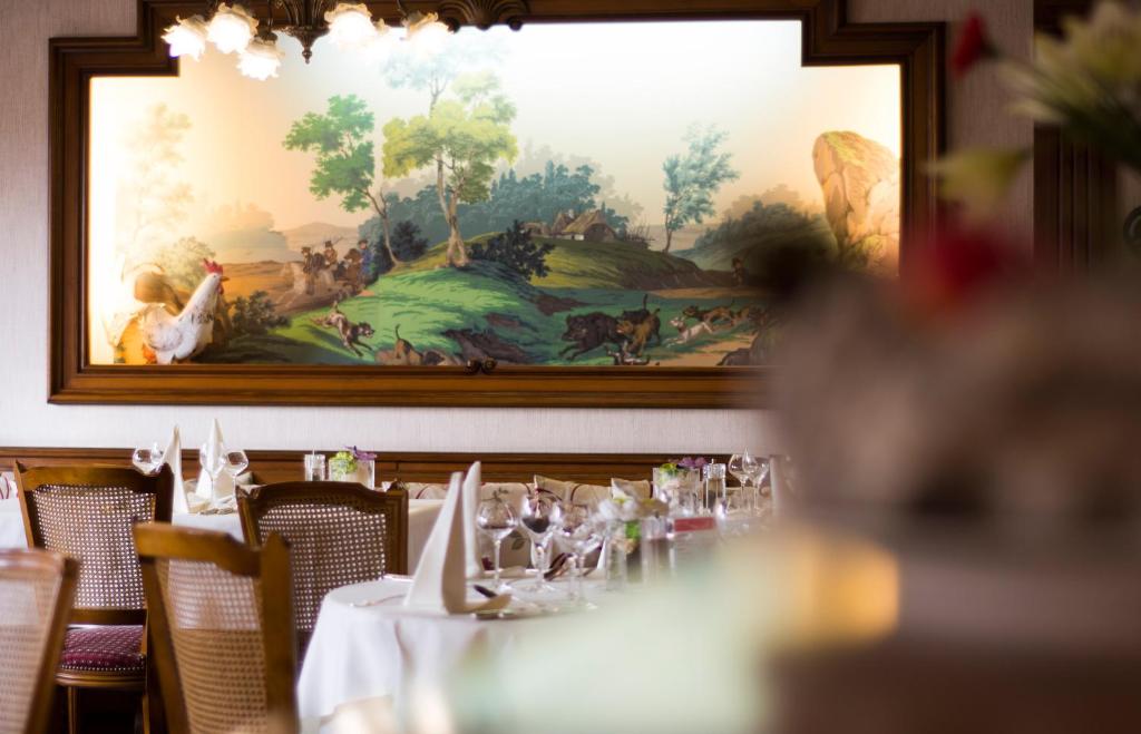 a table in a restaurant with a painting on the wall at Hostellerie Saint Florent in Oberhaslach