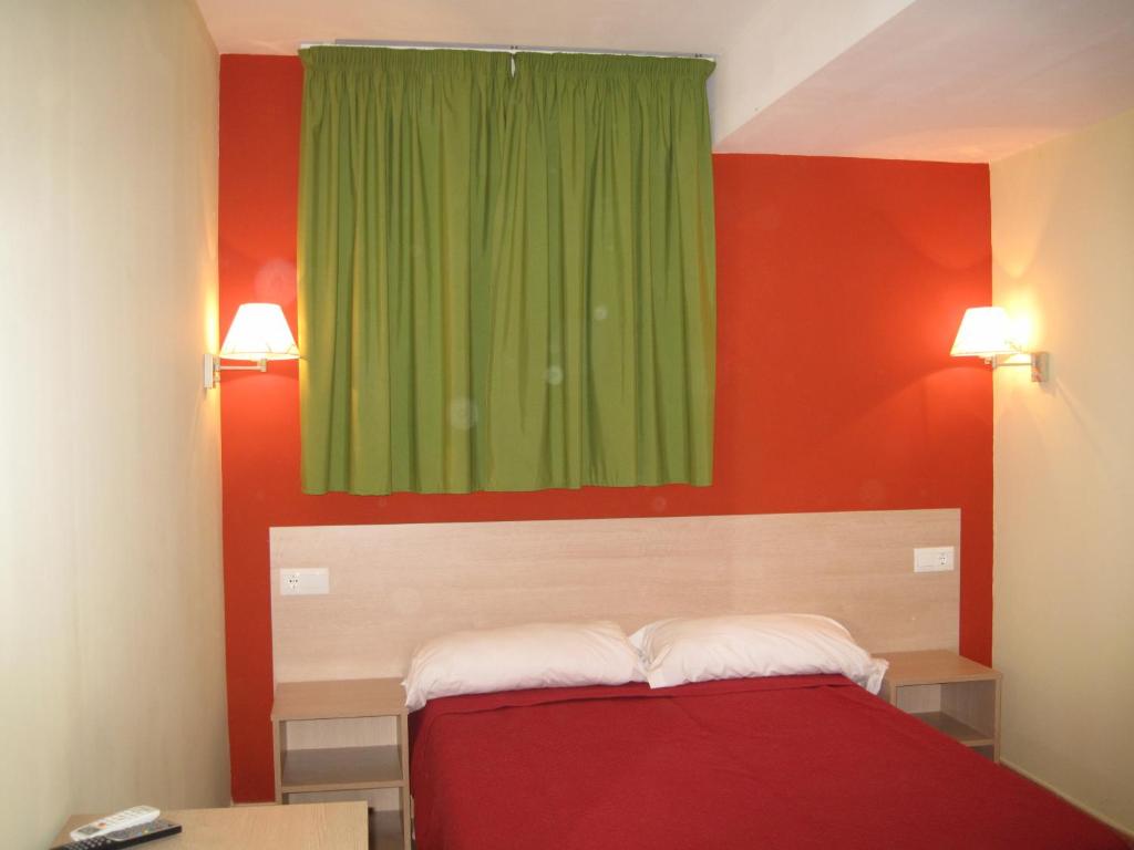 a bedroom with a green window and a red wall at Hostal Ducal in Gandía