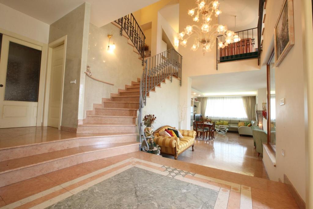een grote woonkamer met een trap en een kroonluchter bij Villa Gioia Rooms in Montegranaro