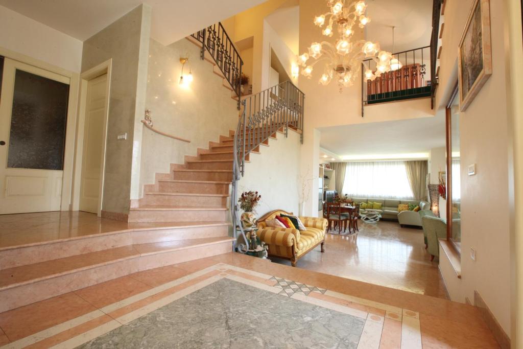 duży salon ze schodami i żyrandolem w obiekcie Villa Gioia Rooms w mieście Montegranaro