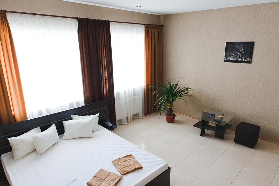a bedroom with a large white bed and windows at Hotel 8th Mile in Dnipro