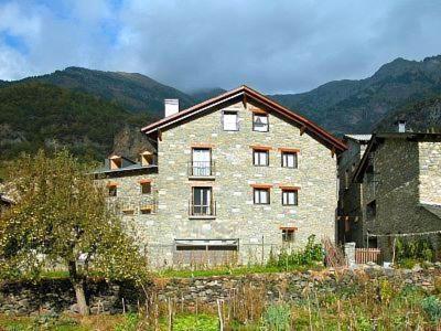 a large stone building with mountains in the background at Apartamentos Estop in Sahun