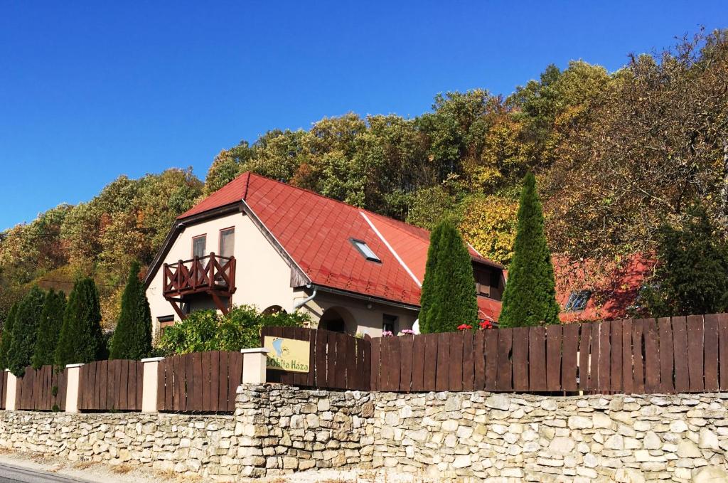 una casa con techo rojo detrás de una valla de piedra en Bóbita Háza en Eplény