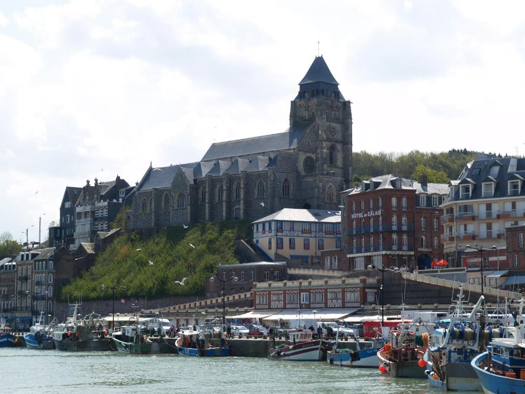 un groupe de bateaux amarrés dans un port avec un grand bâtiment dans l'établissement Hôtel De Calais, au Tréport