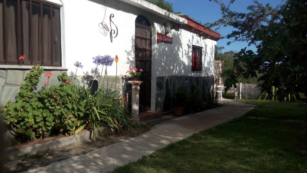 une maison blanche avec des fleurs devant elle dans l'établissement Apart Los Ciruelos, à Huerta Grande
