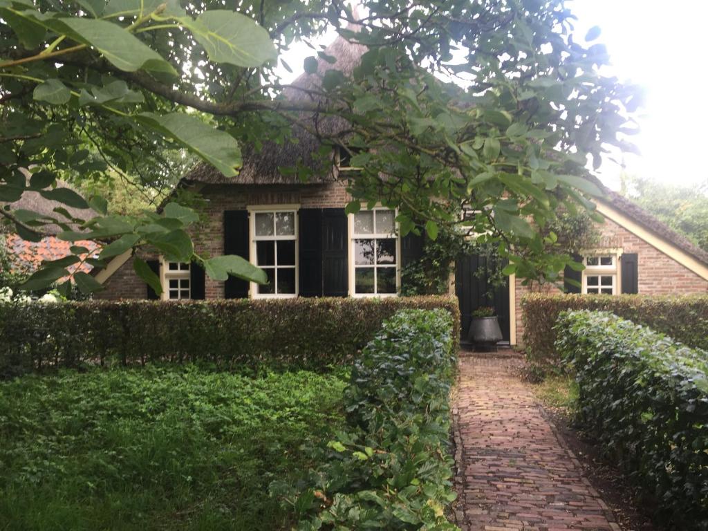 una casa con un camino de ladrillo delante de ella en Boerderij met atelier, en Dalfsen