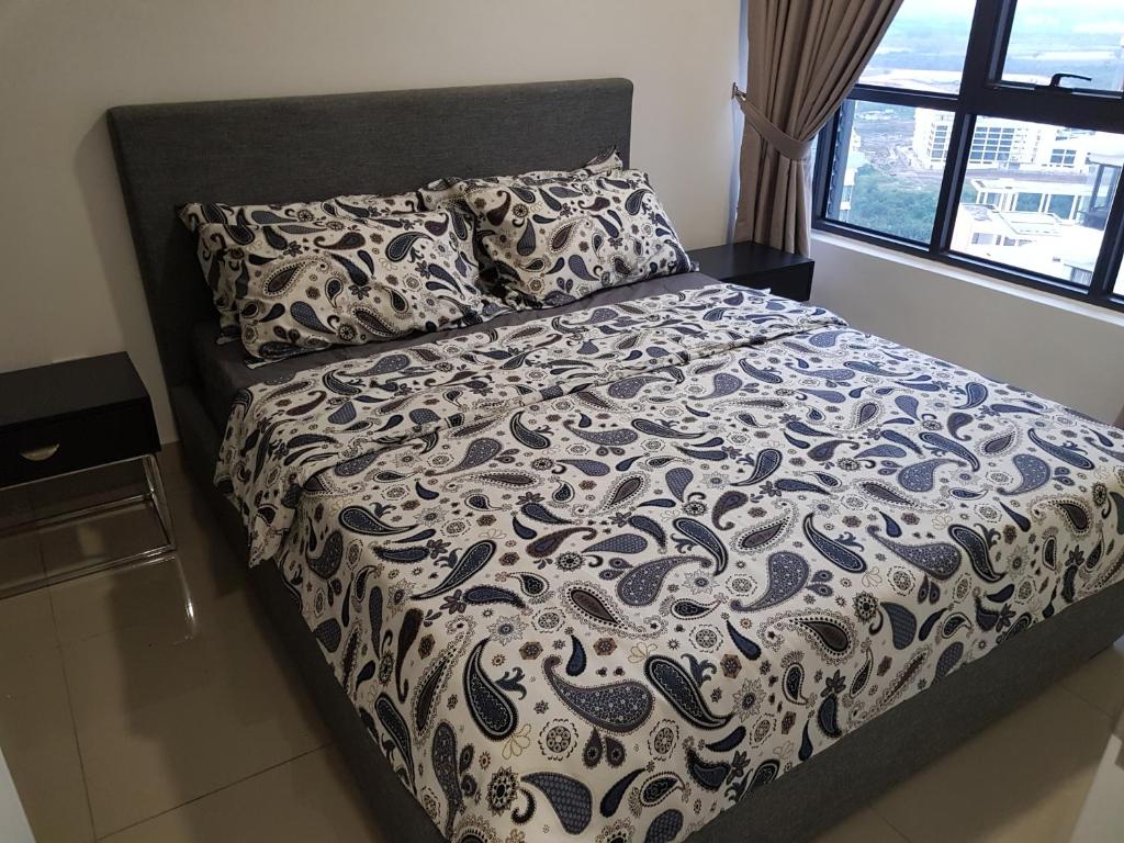 a bed with a black and white comforter and pillows at Relaxing Studio@Cyber in Cyberjaya