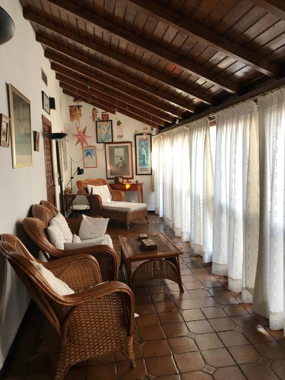 a living room with wicker chairs and tables and windows at Casa longa in Córdoba