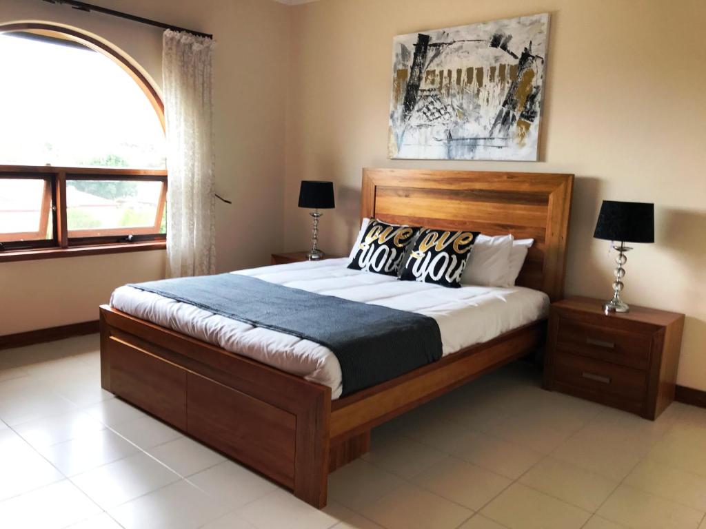 a bedroom with a bed with a wooden headboard and a window at Adelaide's holiday home in Modbury