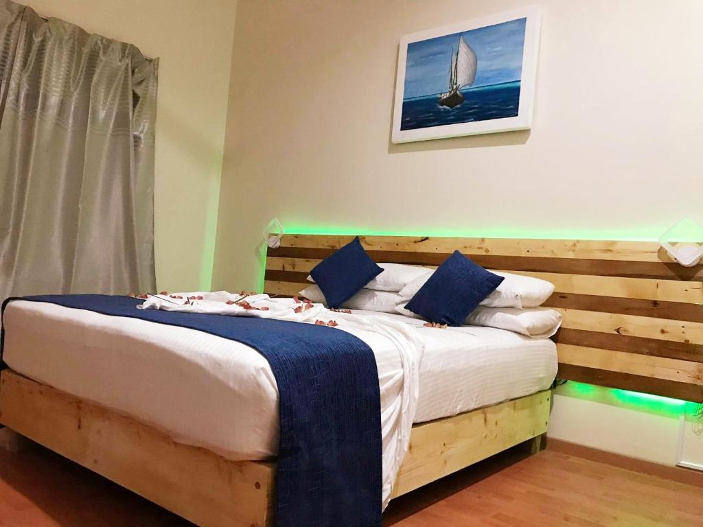 a bedroom with a large bed with a wooden headboard at Fulidhoo La Perla Guest House in Fulidhoo