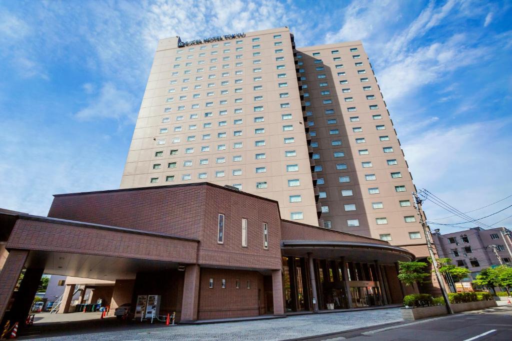a tall white building with a brown building at Sapporo Excel Hotel Tokyu in Sapporo