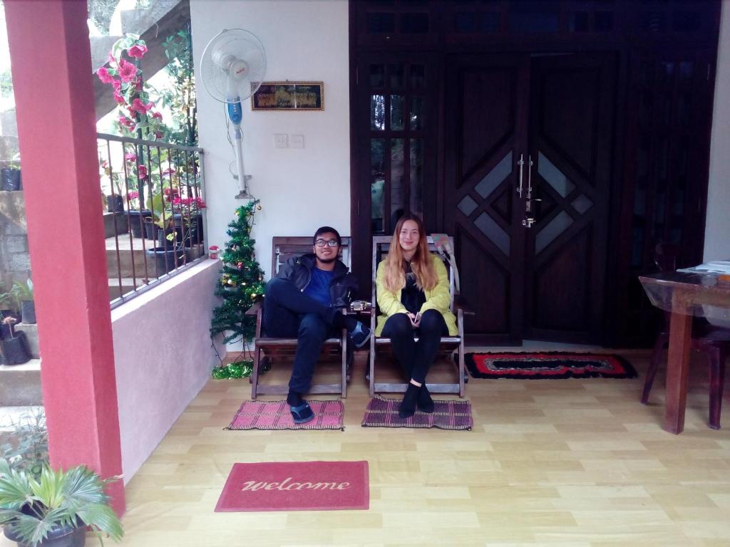 dwie kobiety siedzące w fotelach przed drzwiami w obiekcie Little Cottage w mieście Ella
