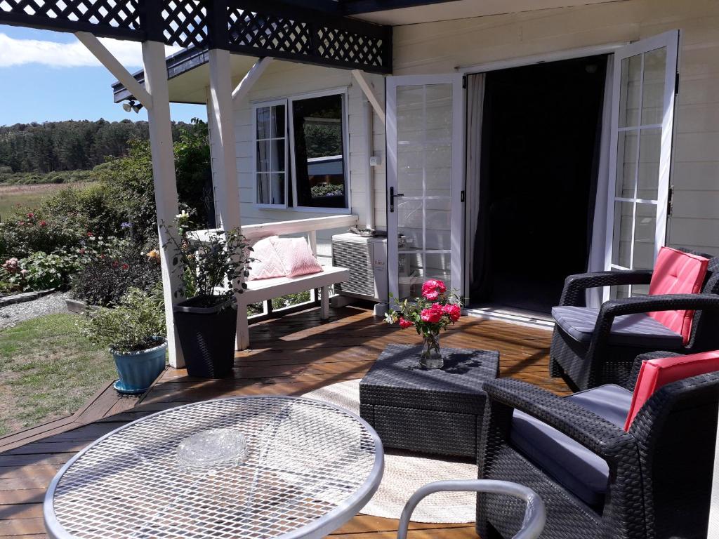 a patio with a table and chairs on a deck at Mont's Cottage in Awatuna