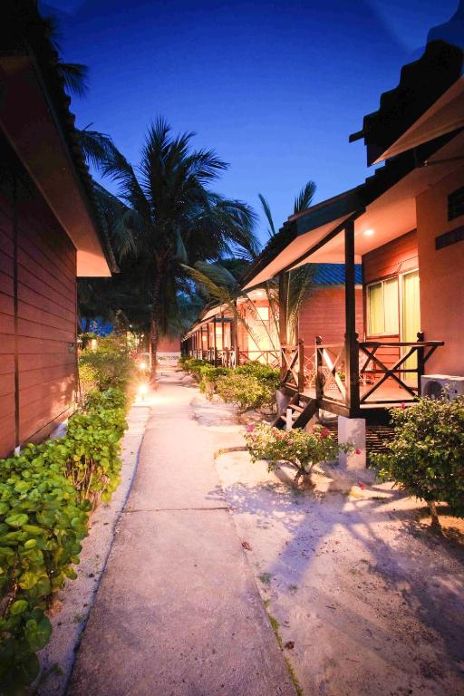a walkway next to a building with palm trees at Tuna Bay Island Resort in Perhentian Islands