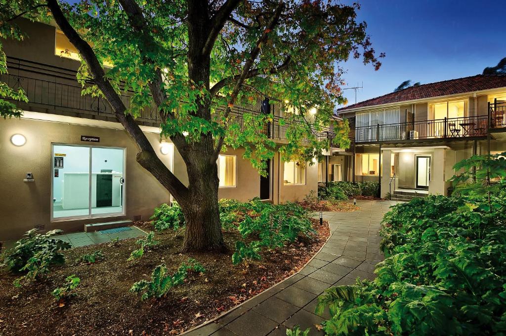 uma passagem em frente a um edifício com uma árvore em Brighton Serviced Apartments em Melbourne