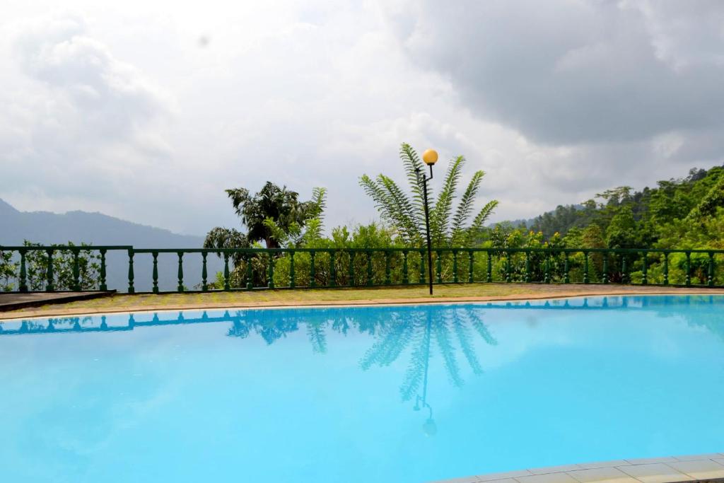 una piscina con una valla y montañas en el fondo en Hotel Breeta's Garden, en Ginigathena