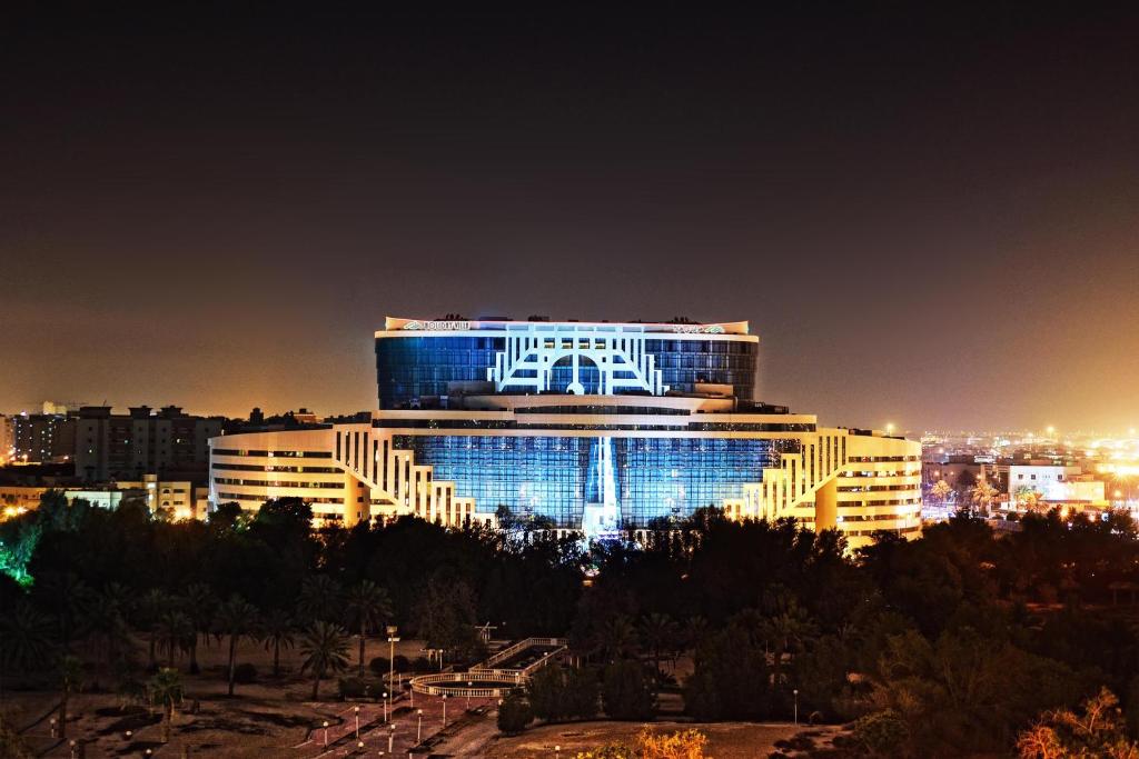 budynek z niebieskimi światłami w nocy w obiekcie Holiday Villa Hotel & Residence City Centre Doha w mieście Doha
