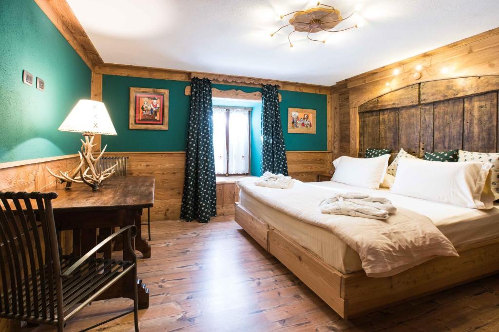 een slaapkamer met een groot bed en een bureau bij Apartments Bucaneve in Breuil-Cervinia