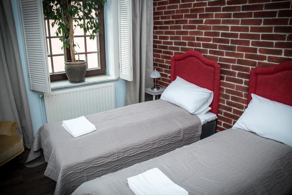 ザモシチにあるPokoje Nad Arkadamiのレンガの壁の客室内のベッド2台