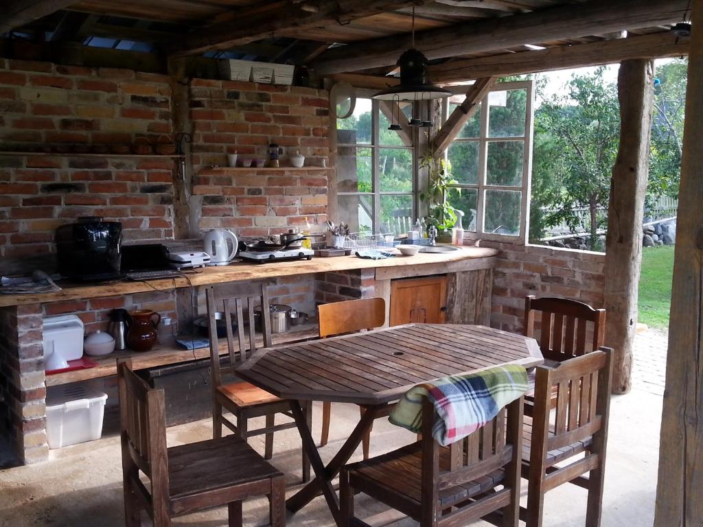 uma cozinha exterior com uma mesa de madeira e cadeiras em Perepuhkus em Kärdla