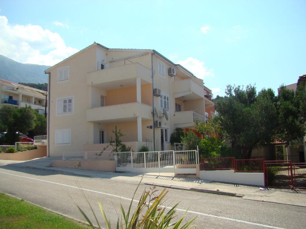 a white apartment building with a fence in front of it at Apartments Ada in Tučepi