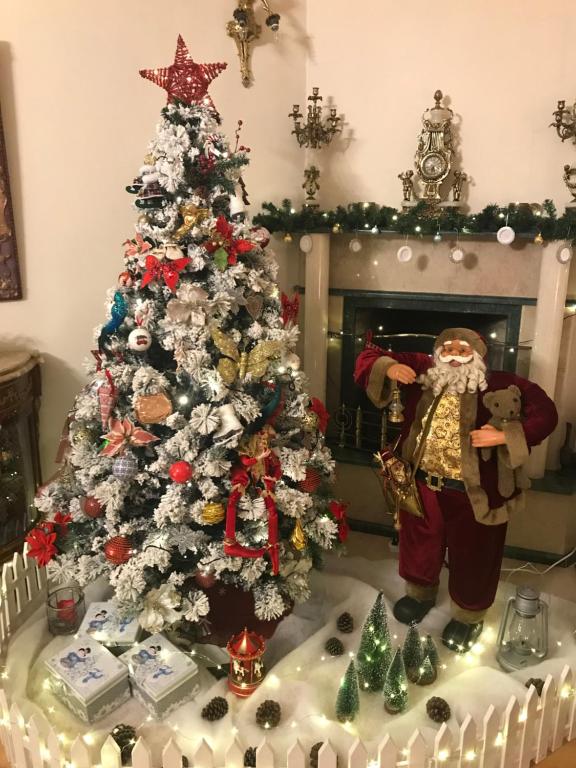 a christmas tree in a living room with presents under it at Apartament Balakhvani in Kutaisi